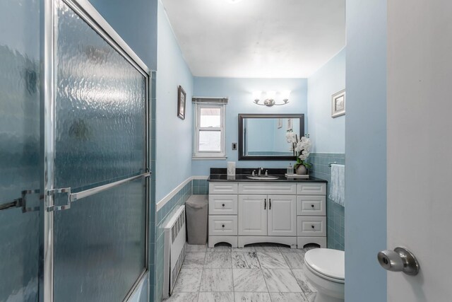 bathroom featuring vanity, toilet, and tile walls