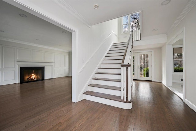 stairway with wood-type flooring and crown molding