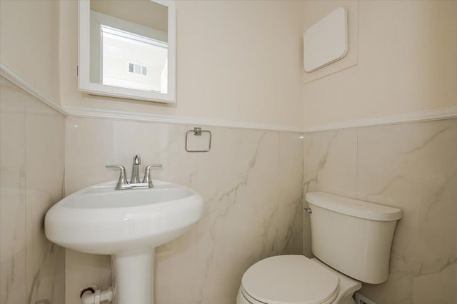 bathroom featuring toilet and tile walls