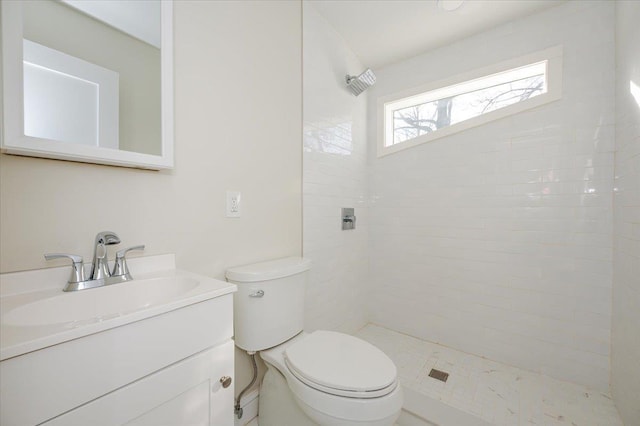 bathroom with vanity, toilet, and a tile shower