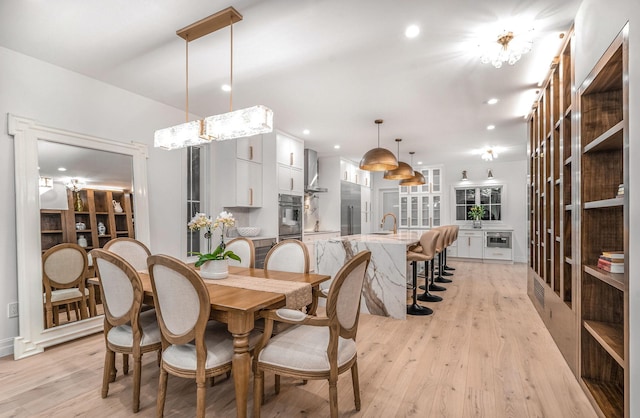 dining room with light wood-type flooring, sink, and an inviting chandelier