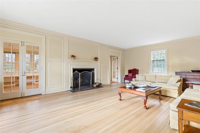 living room with ornamental molding, light hardwood / wood-style flooring, and french doors