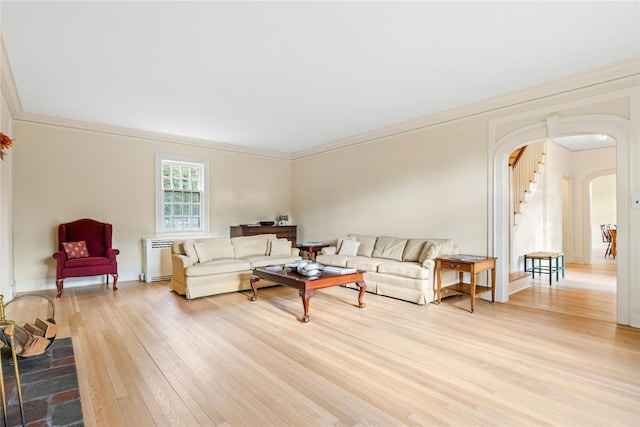 living room featuring hardwood / wood-style floors, crown molding, and radiator