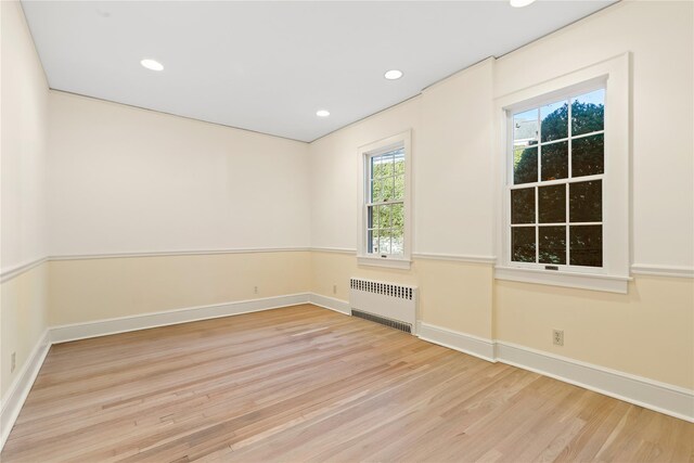 spare room featuring radiator heating unit and light hardwood / wood-style floors