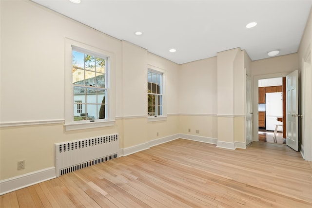 empty room with light wood-type flooring and radiator heating unit