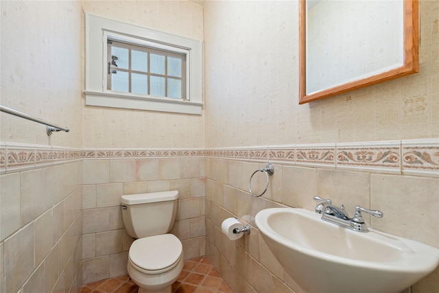 bathroom featuring toilet, tile walls, and sink