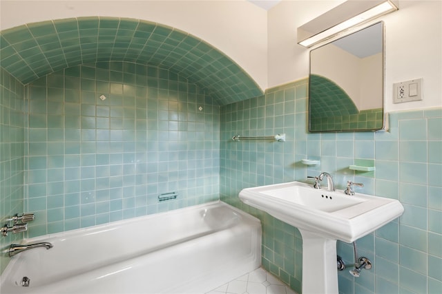 bathroom with a bathing tub, tile walls, and tile patterned floors