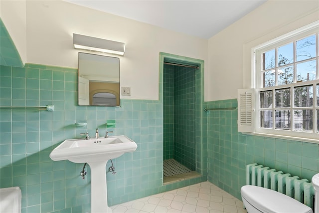 bathroom with a tile shower, radiator, tile patterned floors, toilet, and tile walls