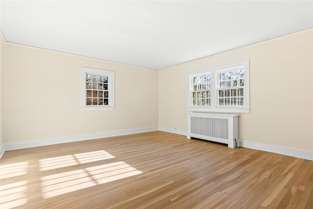 empty room featuring radiator and light hardwood / wood-style flooring