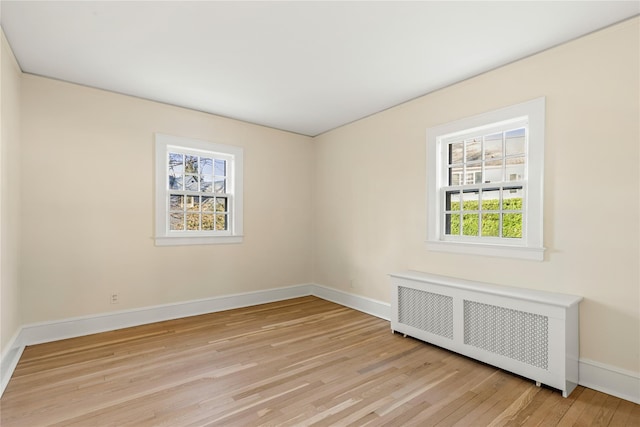 empty room with radiator heating unit and light hardwood / wood-style floors