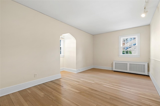 empty room with radiator heating unit and light hardwood / wood-style flooring