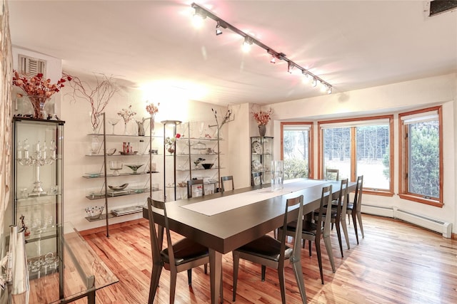 dining area featuring track lighting, a baseboard radiator, and light hardwood / wood-style floors