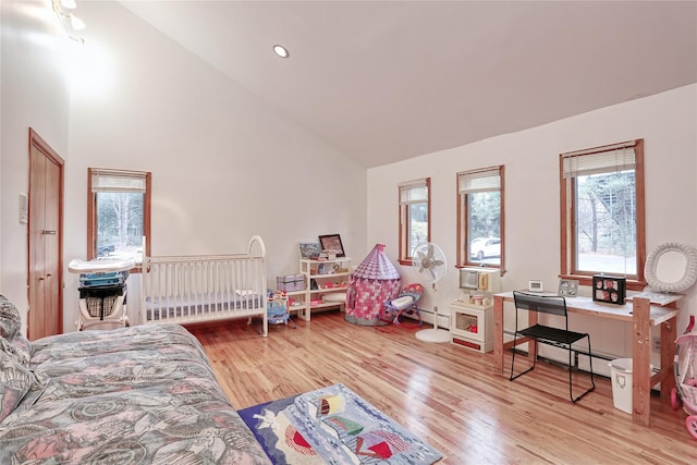 bedroom with baseboard heating, high vaulted ceiling, and light hardwood / wood-style floors