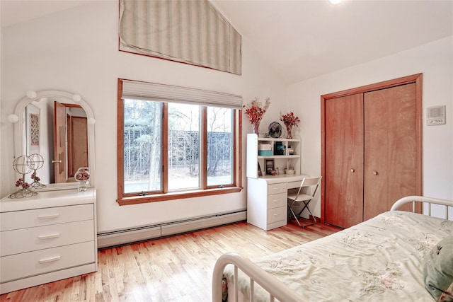 bedroom featuring baseboard heating, a closet, light hardwood / wood-style flooring, and lofted ceiling