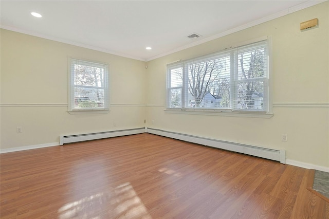 empty room featuring baseboard heating, ornamental molding, a healthy amount of sunlight, and wood-type flooring