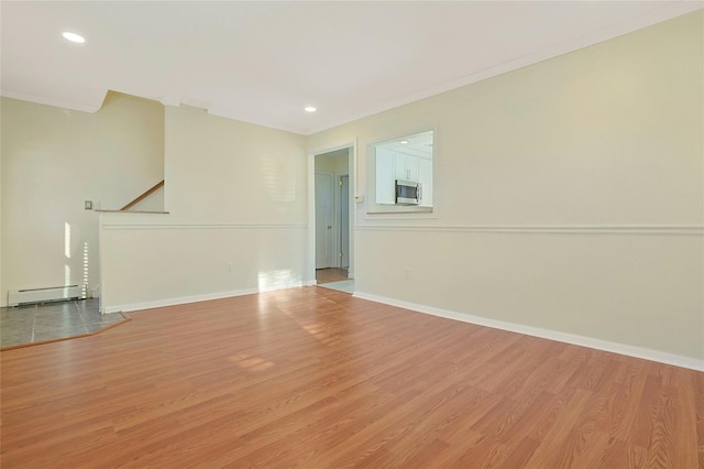 empty room with ornamental molding, baseboard heating, and light hardwood / wood-style flooring