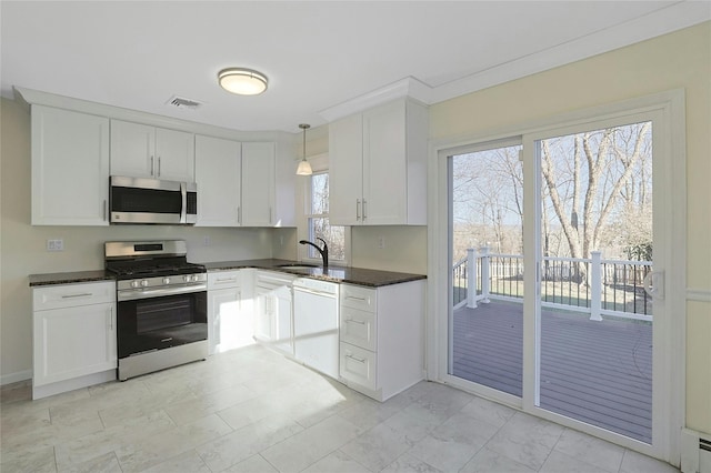 kitchen featuring sink, hanging light fixtures, stainless steel appliances, dark stone countertops, and white cabinets