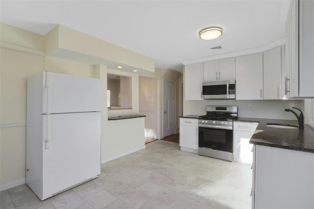 kitchen with sink, white cabinets, dark stone counters, and appliances with stainless steel finishes