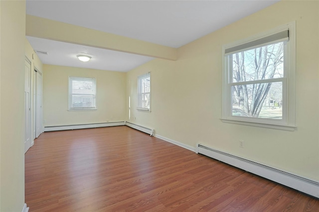 spare room with a wealth of natural light, hardwood / wood-style flooring, and a baseboard heating unit