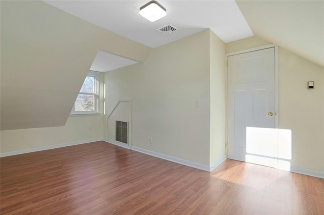 additional living space with hardwood / wood-style flooring and vaulted ceiling