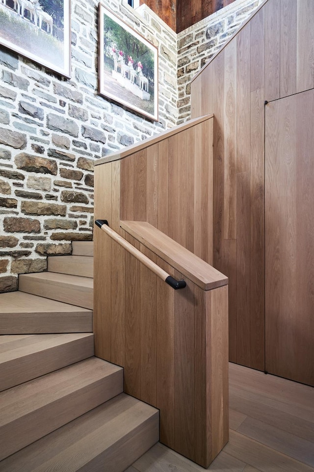 stairway with wood walls and hardwood / wood-style flooring