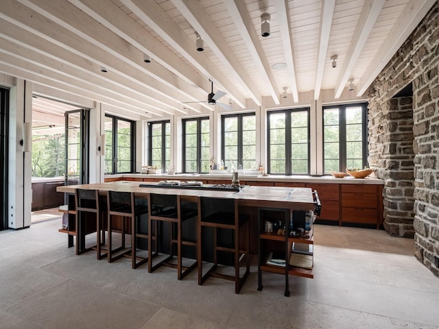 interior space with ceiling fan, plenty of natural light, beamed ceiling, and wooden counters