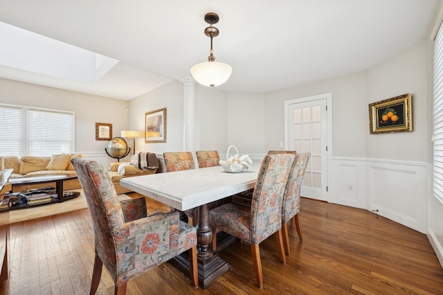 dining space with ornate columns and dark wood-type flooring