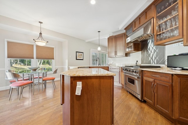 kitchen with high end stainless steel range, decorative light fixtures, range hood, and light hardwood / wood-style floors