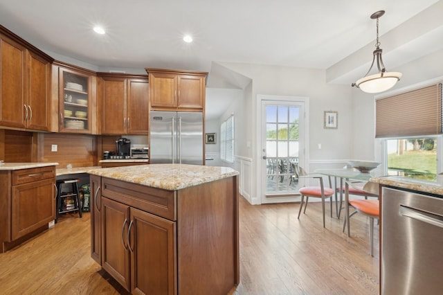 kitchen with pendant lighting, stainless steel appliances, a wealth of natural light, and light hardwood / wood-style floors