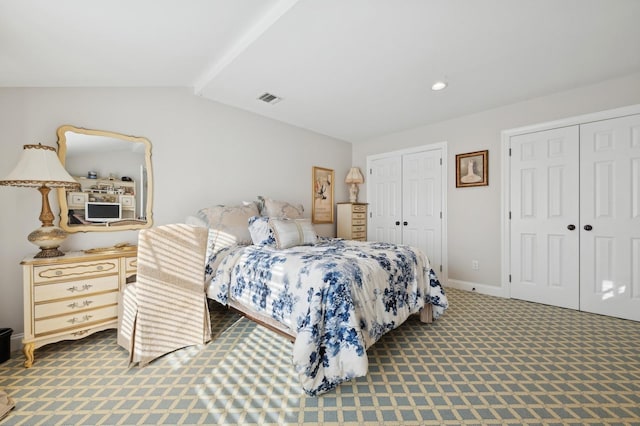 bedroom with carpet, two closets, and vaulted ceiling