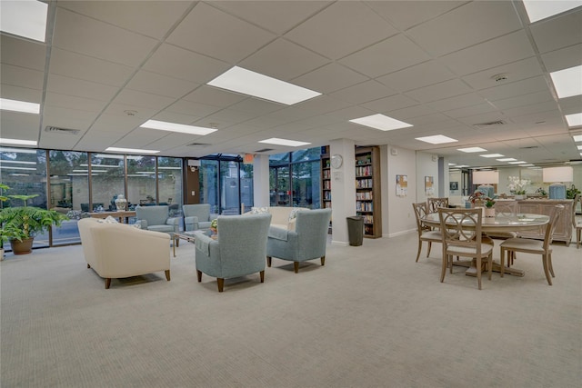 carpeted living room featuring a wall of windows and a drop ceiling