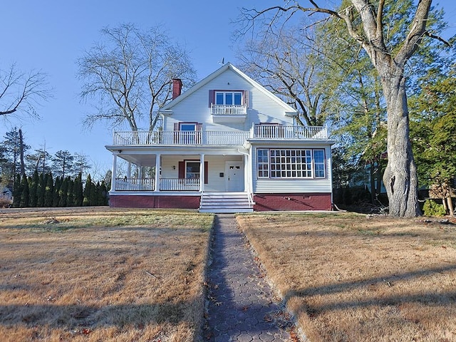 view of front of house with a porch, a balcony, and a front yard