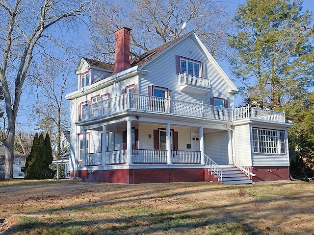 view of front of home featuring a balcony, a front lawn, and covered porch