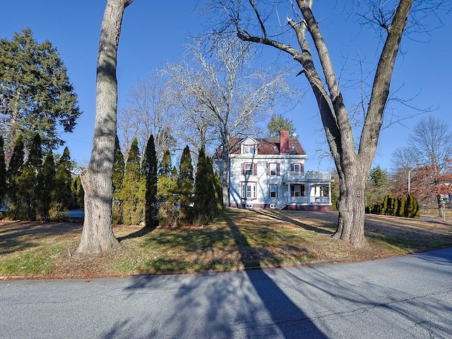 view of front facade featuring a balcony and a front yard