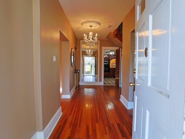 doorway to outside with dark wood-type flooring and ceiling fan with notable chandelier