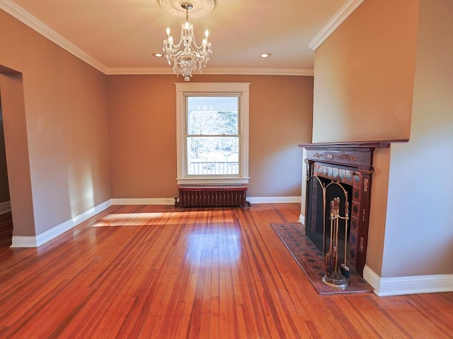 unfurnished living room with hardwood / wood-style flooring, an inviting chandelier, radiator, and ornamental molding