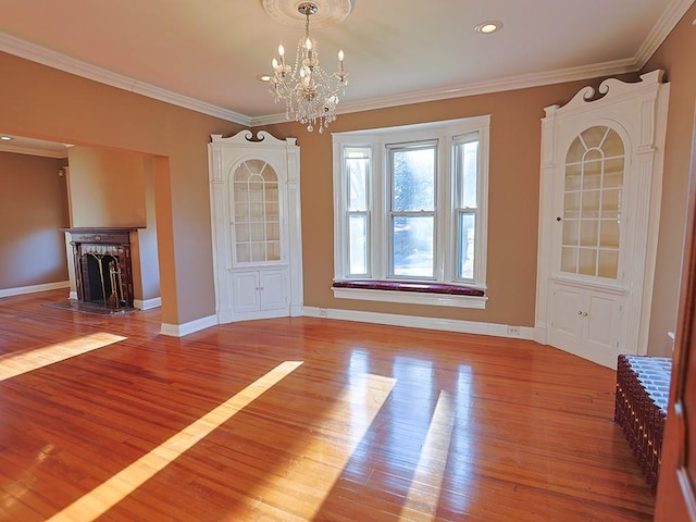 unfurnished dining area featuring a chandelier, a fireplace, light hardwood / wood-style floors, and ornamental molding