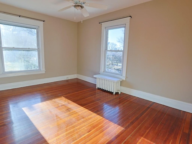 unfurnished room with dark hardwood / wood-style flooring, ceiling fan, and radiator heating unit