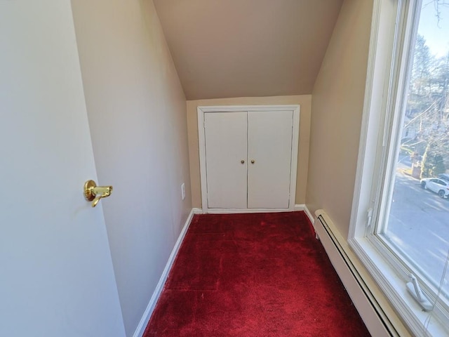 doorway featuring dark colored carpet, lofted ceiling, and a baseboard radiator