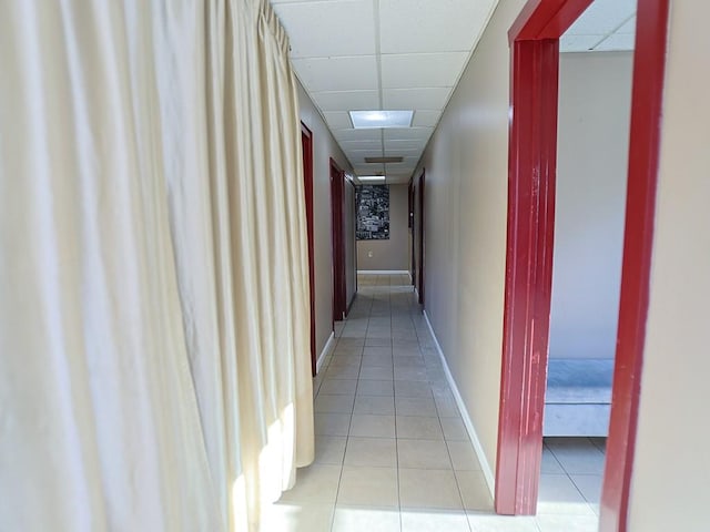 corridor featuring a drop ceiling and light tile patterned floors