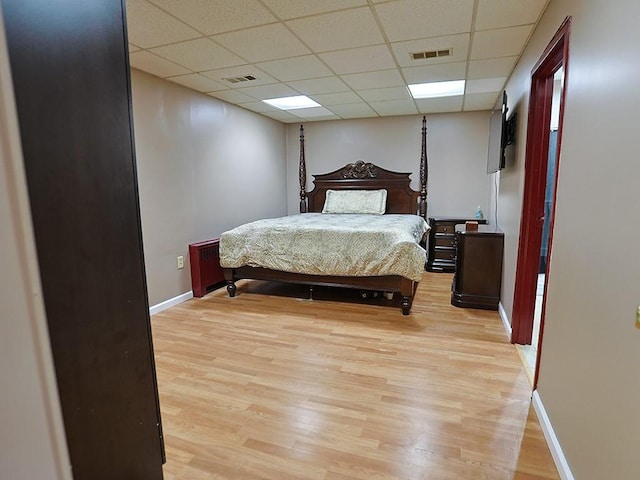 bedroom featuring light hardwood / wood-style flooring and a drop ceiling