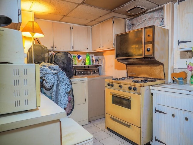 kitchen with gas range gas stove, independent washer and dryer, pendant lighting, a paneled ceiling, and light tile patterned floors