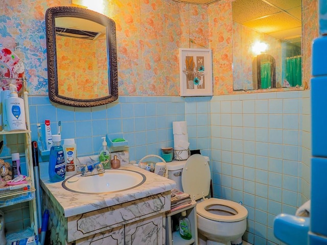 bathroom with a shower with curtain, vanity, toilet, and tile walls