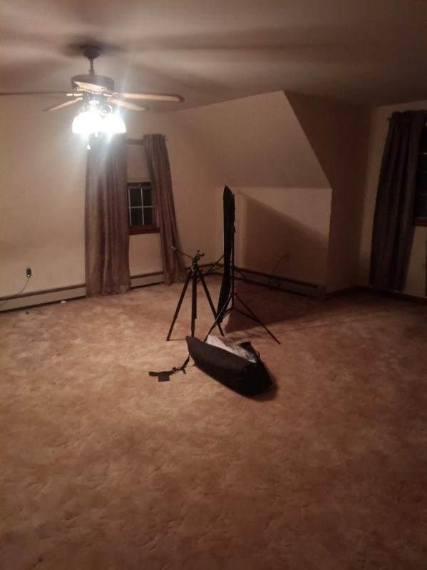 additional living space featuring ceiling fan and a baseboard heating unit