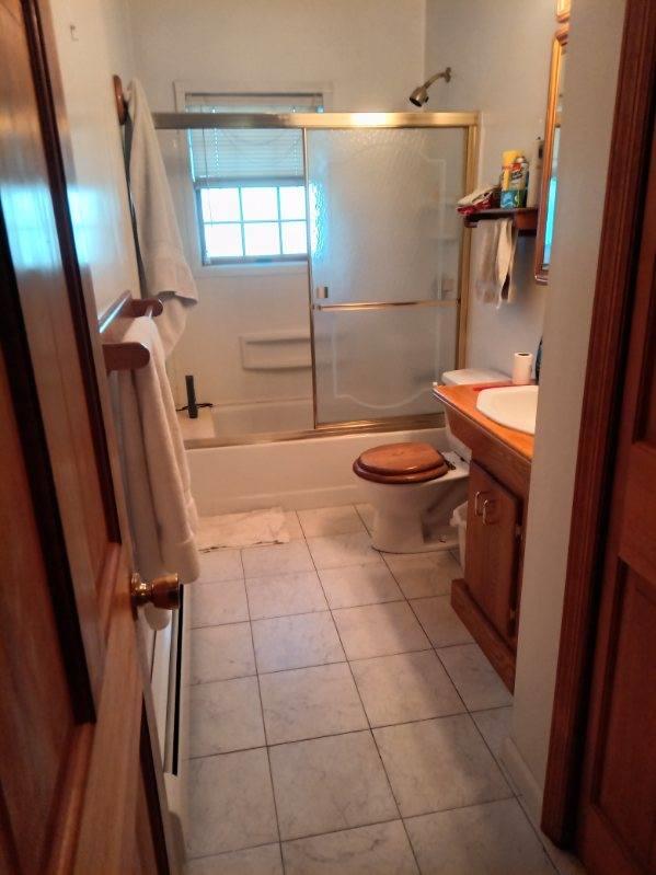 full bathroom with tile patterned floors, vanity, bath / shower combo with glass door, and toilet