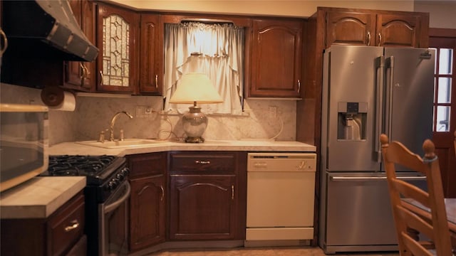 kitchen with dark brown cabinetry, exhaust hood, stainless steel appliances, decorative backsplash, and sink