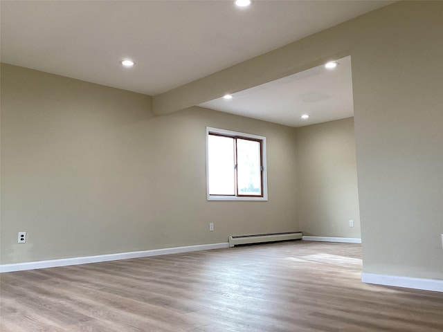 empty room featuring light wood-type flooring and a baseboard radiator