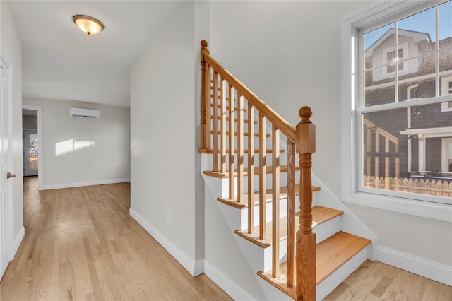 stairway featuring a wall unit AC and wood-type flooring