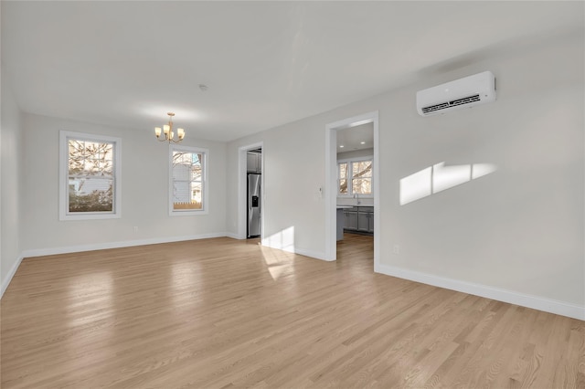 empty room featuring a wall mounted air conditioner, light hardwood / wood-style floors, and a chandelier