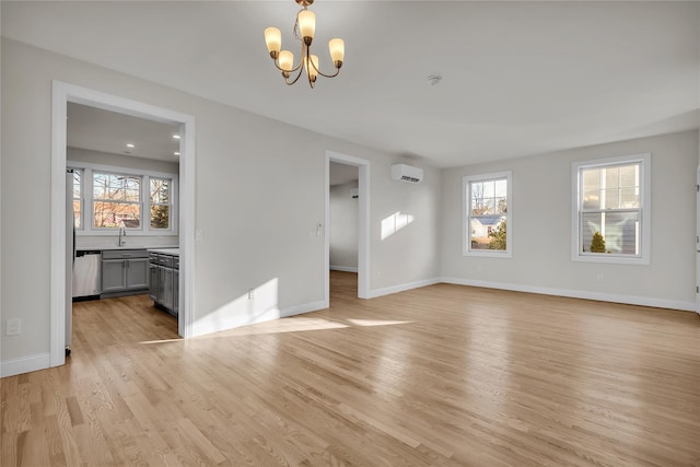 interior space with an AC wall unit, a chandelier, a healthy amount of sunlight, and light wood-type flooring